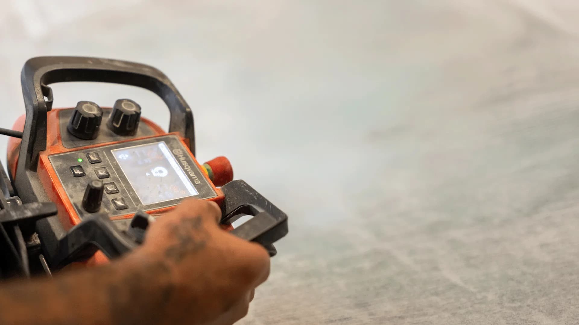 Close-up of Husqvarna remote-operated concrete grinder with operator in background