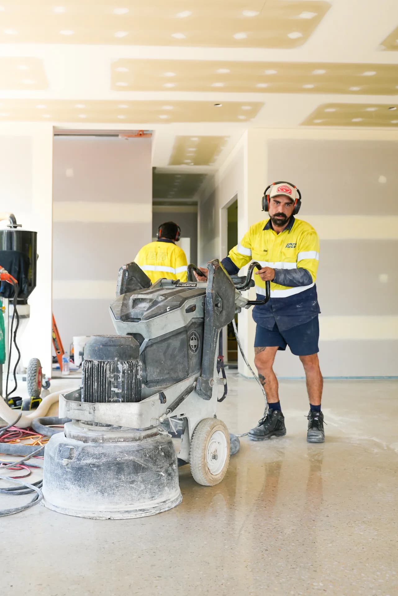 Two ICGC crew members in yellow hi-vis with Husqvarna polishing equipment on a Brisbane commercial project