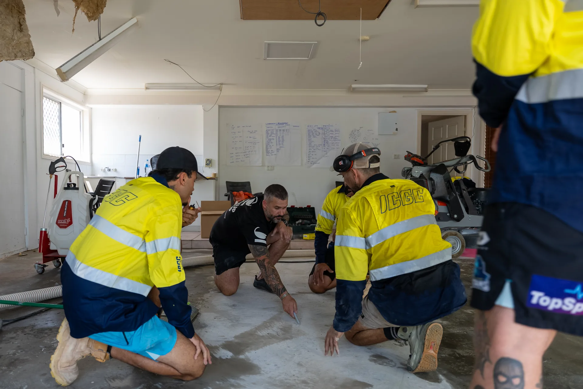 ICGC crew crouching to inspect a freshly polished concrete floor during team training day