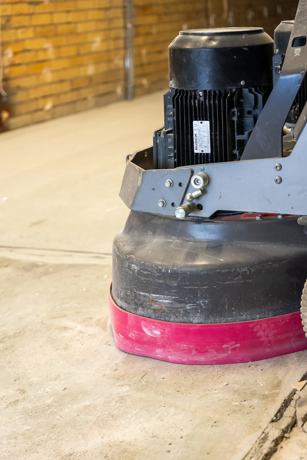 Planetary concrete grinder with dust shroud on a raw concrete slab at a Gold Coast commercial site