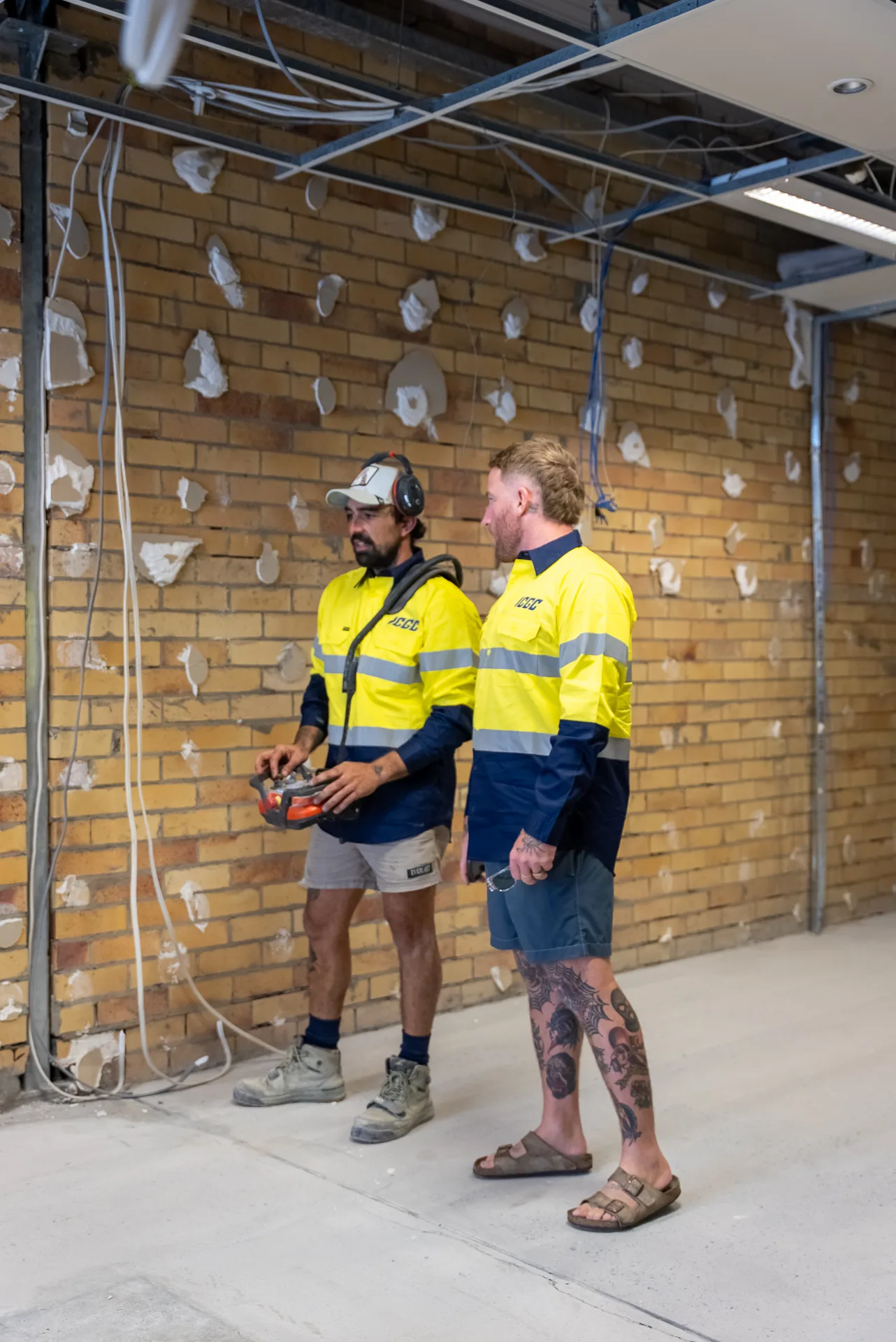 Two ICGC team members standing in front of exposed brick wall on a Gold Coast commercial concrete grinding project