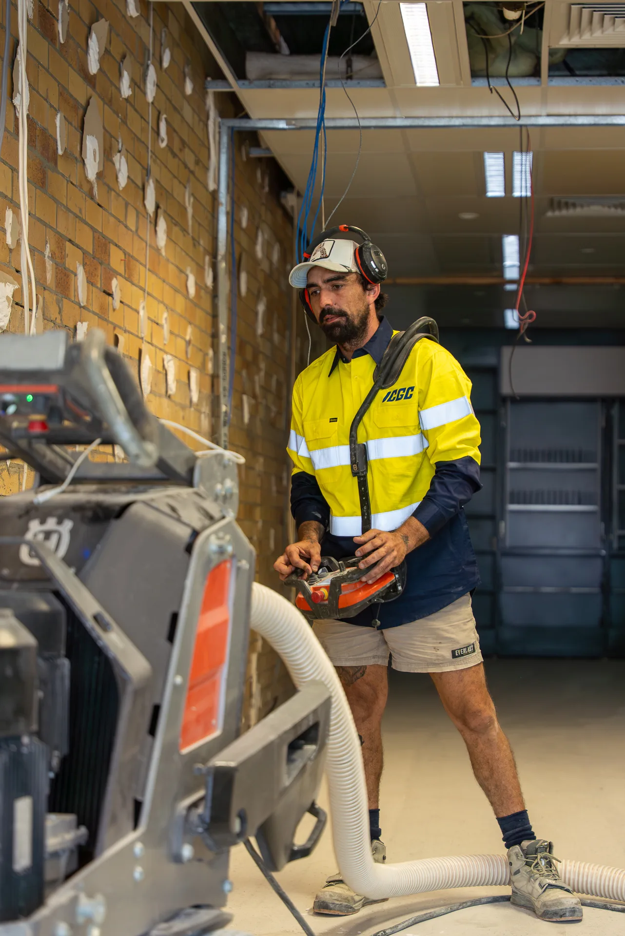 ICGC operator with Husqvarna planetary grinder and edge grinder at a commercial fitout with exposed brick
