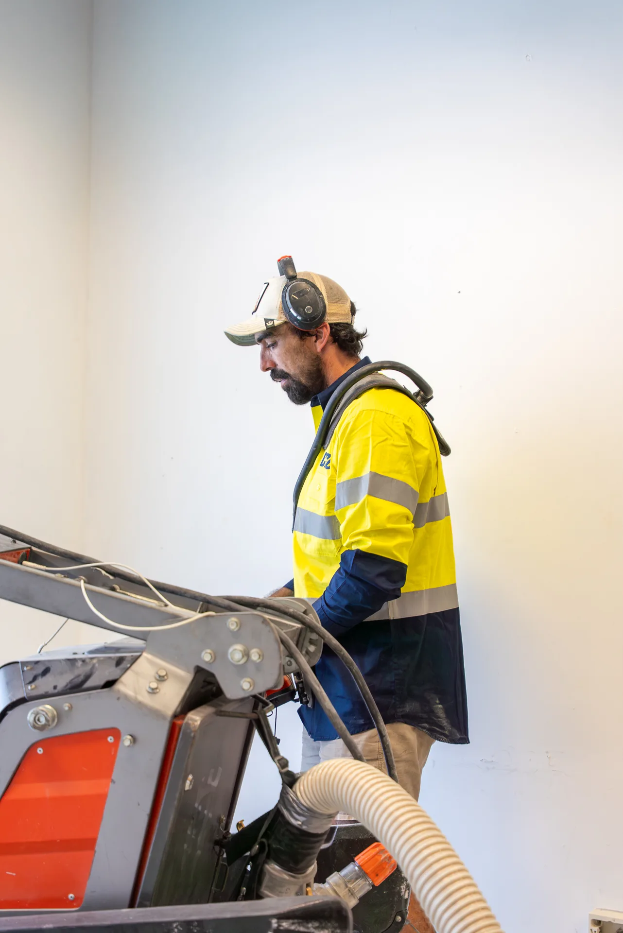 ICGC operator guiding a Husqvarna planetary concrete grinder across a commercial floor with dust extraction
