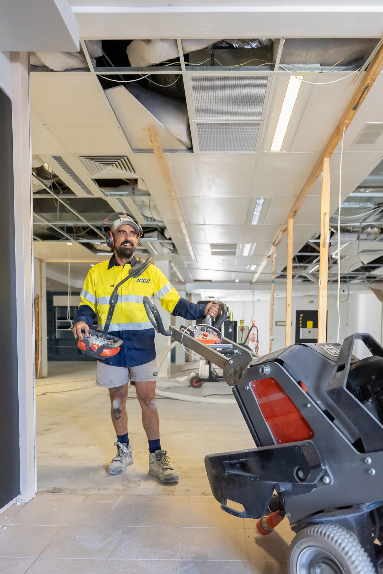 Industrial dust extraction hose connected to a concrete grinder on a commercial floor being prepared