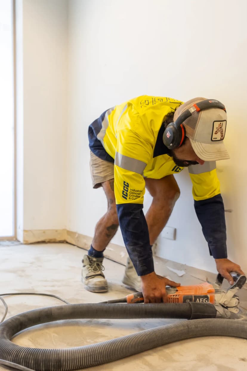 Dust-free concrete grinding setup with HEPA extraction hose on a clean commercial site floor
