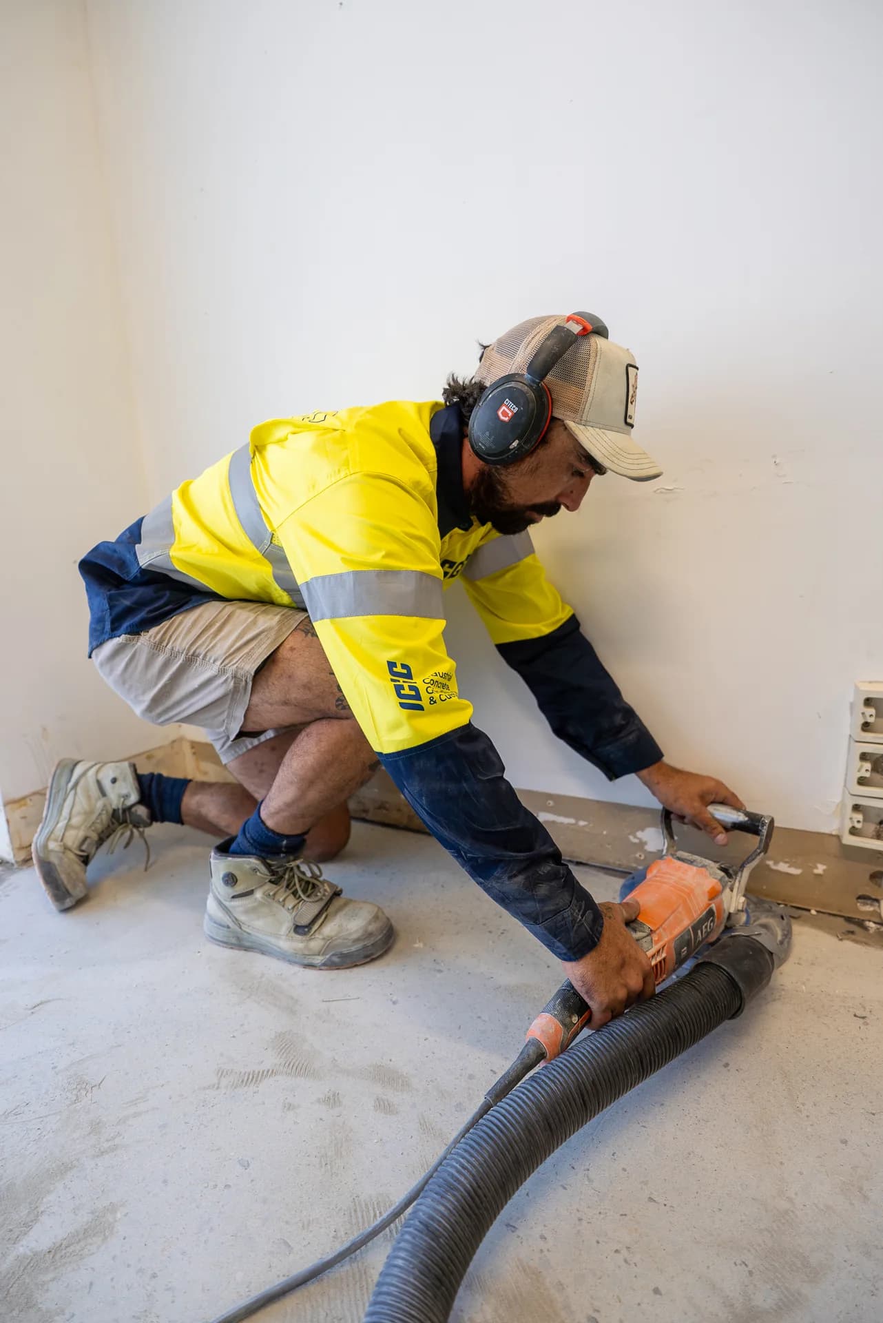 ICGC operator using an edge grinder with dust extraction along a wall on a Gold Coast commercial site